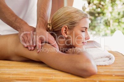 Woman receiving shoulder massage at spa center