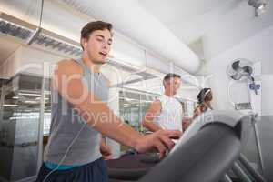 Fit man running on treadmill listening to music