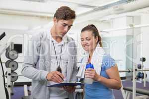 Personal trainer and client looking at clipboard together