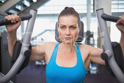 Fit brunette using weights machine for arms