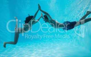 Couple holding hands and swimming underwater