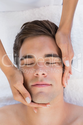 Man receiving facial massage at spa center