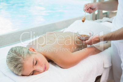 Attractive woman receiving spa treatment with honey