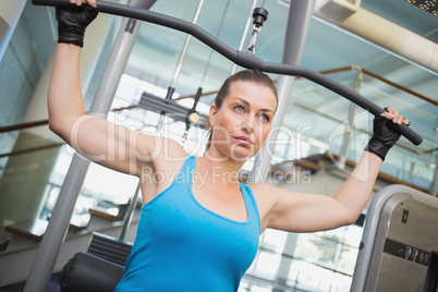 Fit brunette using weights machine for arms