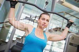 Fit brunette using weights machine for arms