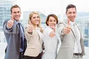 Business people gesturing thumbs up in office