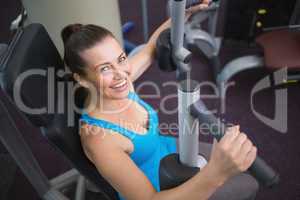 Fit brunette using weights machine for arms