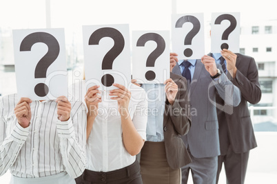 Business people holding question mark signs in office