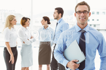 Smiling businessman with colleagues behind