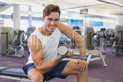 Fit man lifting dumbbells sitting on the bench