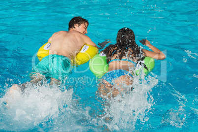 Couple in inflatable rings at swimming pool