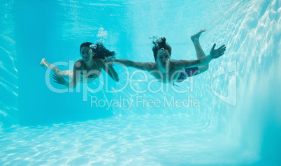 Couple holding hands and swimming underwater