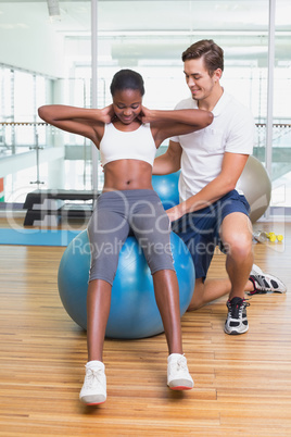 Personal trainer working with client on exercise ball