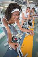 Three fit people working out on exercise bikes