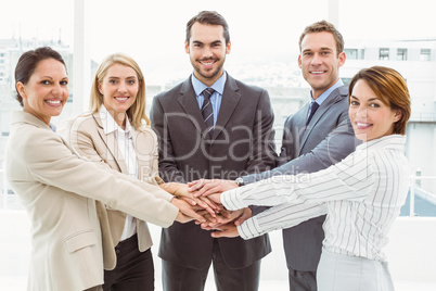 Happy executives holding hands together in office