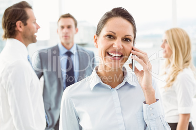 Businesswoman using mobile phone with colleagues behind