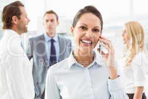 Businesswoman using mobile phone with colleagues behind