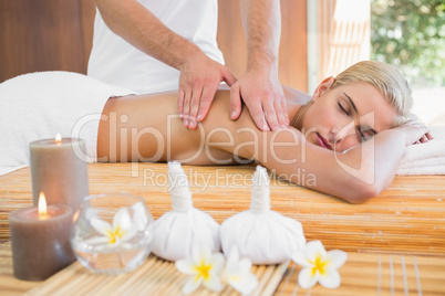 Woman receiving back massage at spa center