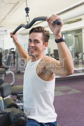 Fit man using the weights machine for his arms