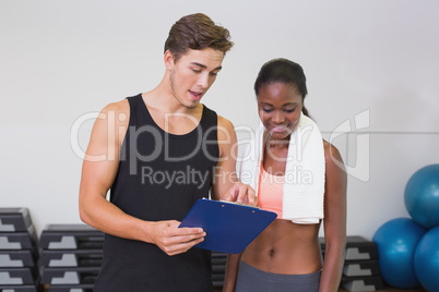 Personal trainer and client looking at clipboard together