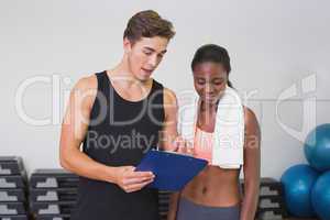 Personal trainer and client looking at clipboard together