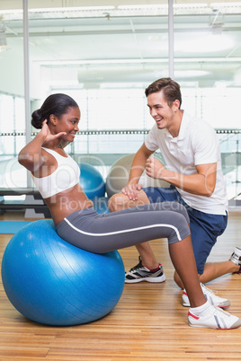 Personal trainer working with client on exercise ball