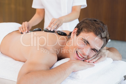 Young man receiving stone massage at spa center