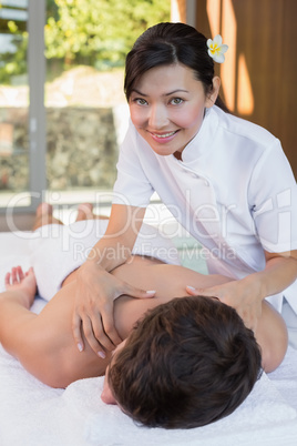 Female masseur massaging mans back at spa center