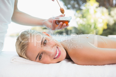 Attractive woman receiving spa treatment with honey