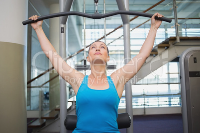 Fit brunette using weights machine for arms