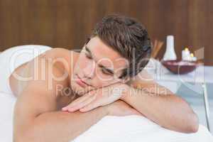 Man lying on massage table at spa center