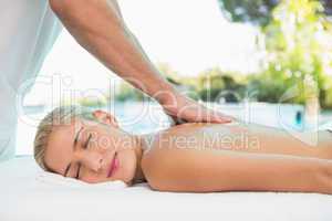 Woman receiving back massage at spa center