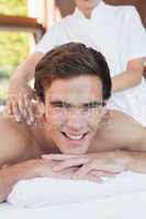 Handsome man receiving shoulder massage at spa center