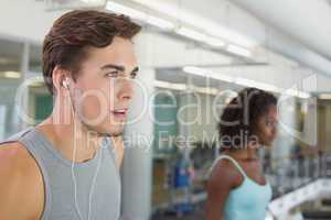 Fit man running on treadmill listening to music