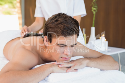 Man receiving stone massage at spa center