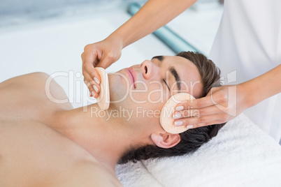 Man receiving facial massage at spa center