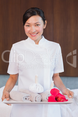 Confident masseur holding rolled up towels