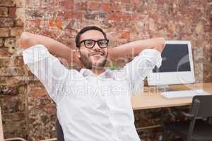Businessman with hands behind head in office