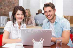 Smiling business people working together with laptop
