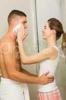 Woman putting shaving foam on boyfriends face