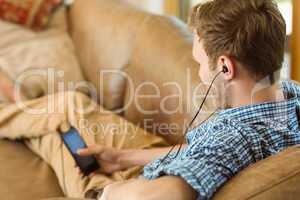 Young man listening to music on his couch