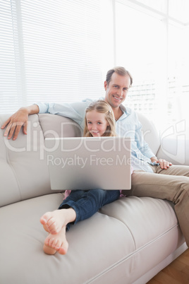 Casual father and daughter using laptop on the couch