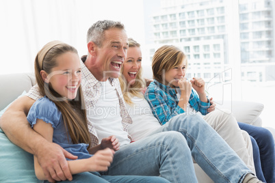 Excited family watching television on sofa