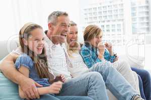 Excited family watching television on sofa