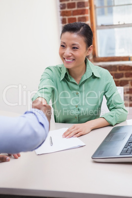 Casual business people shaking hands at desk