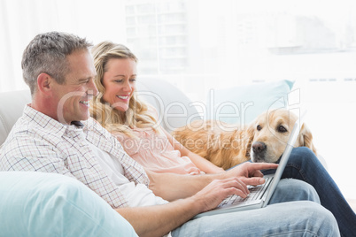 Couple using laptop and spending time with their dog