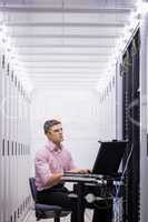 Technician sitting on swivel chair using laptop to diagnose serv