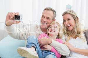 Cheerful family taking self pictures with a digital camera
