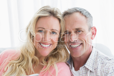 Happy couple relaxing on the couch smiling at camera Happy couple relaxing on the couch smiling at camera