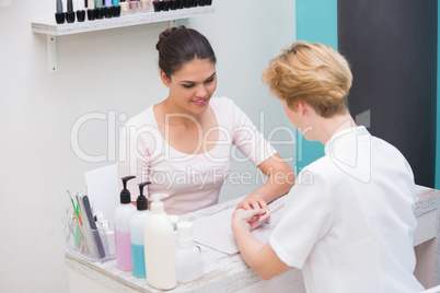 Pretty nail technician filing customers nails